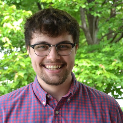 Tyler Jubar smiling, with trees behind him